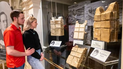Two visitors viewing the largest collection of recovered Titanic life jackets on display at the Titanic Museum.