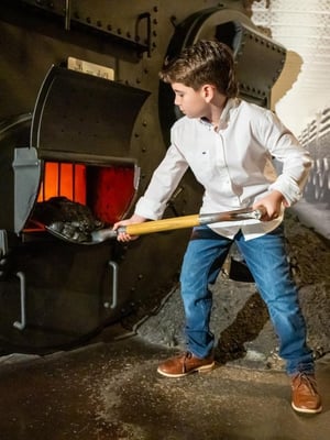 An image of a young guest shoveling coal at the Titanic Museum Attraction