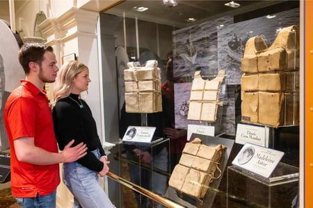 Two visitors viewing the largest collection of recovered Titanic life jackets on display at the Titanic Museum.