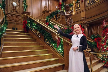 A first-class maid is welcoming you to the Grand Staircase decorated for Christmas at the Titanic Museum Attraction.