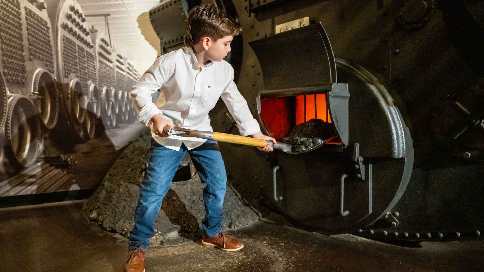 Young boy shovels coal into the boiler in the Titanic Museum Attraction.
