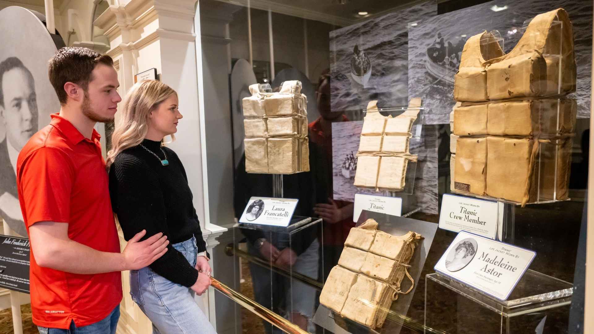 Two visitors viewing the largest collection of recovered Titanic life jackets on display at the Titanic Museum.